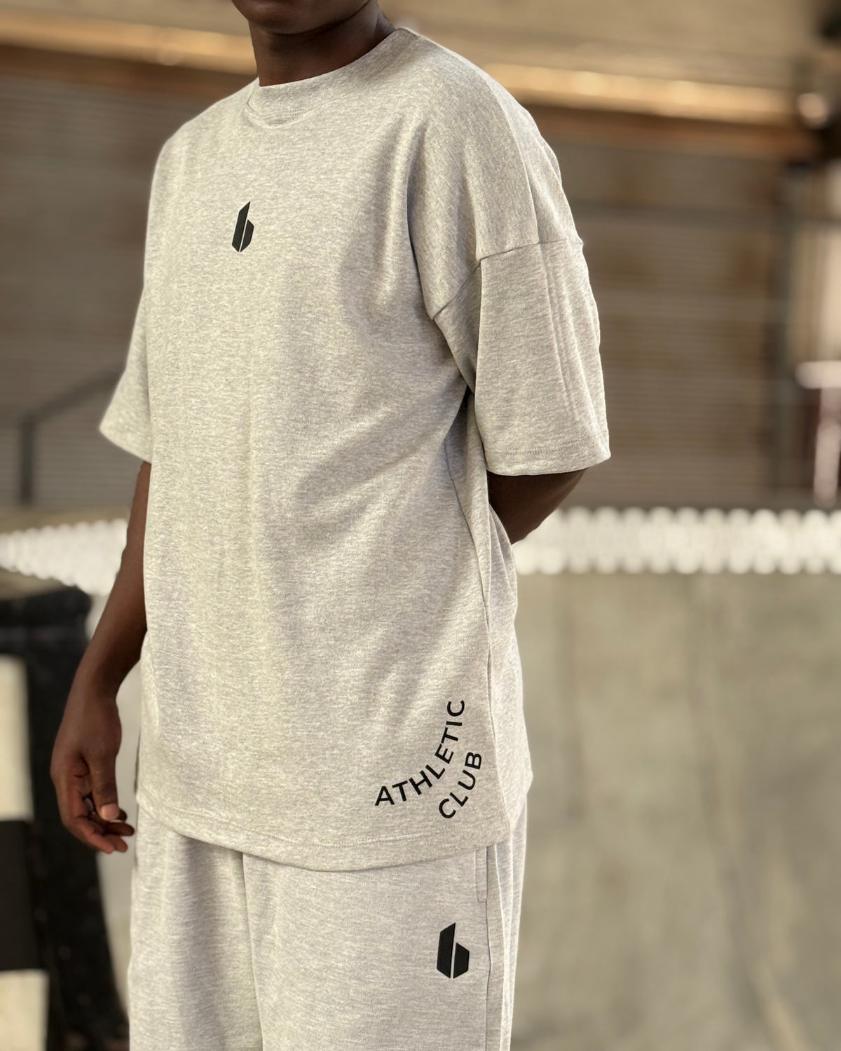 Person wearing a gray athletic club outfit with a logo on a blurred background