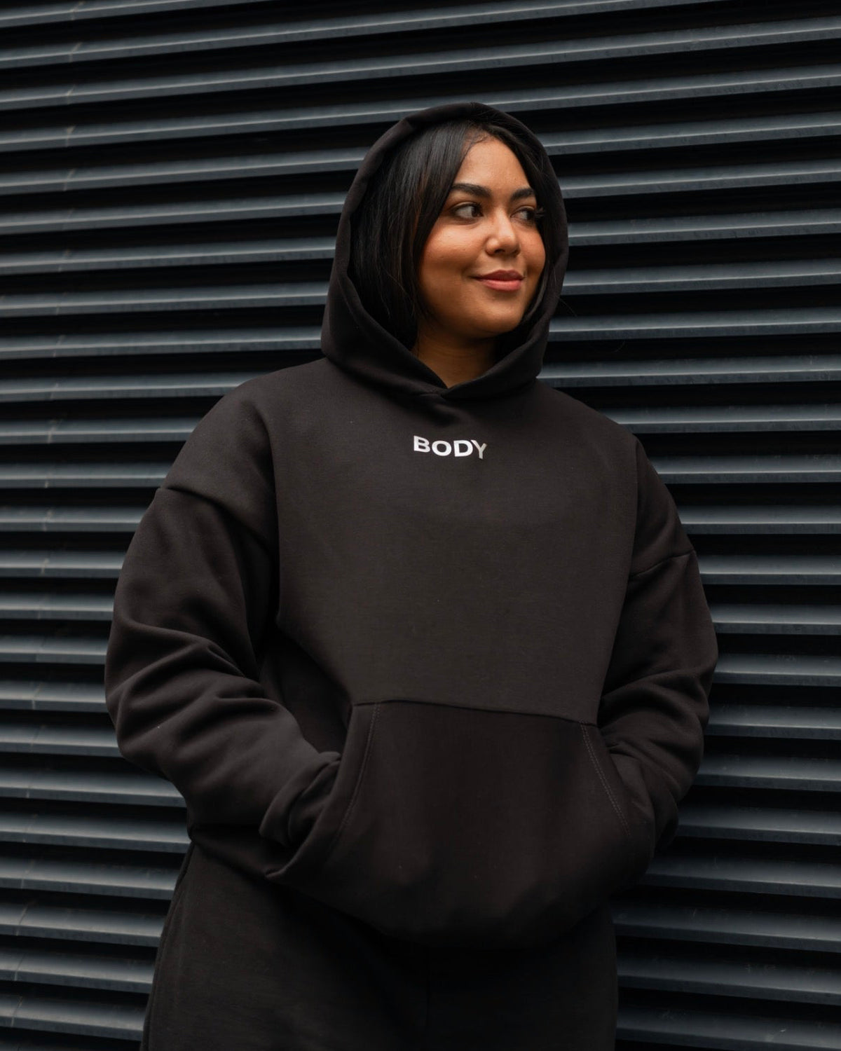 Person wearing a black hoodie with 'BODY' text against a metallic background