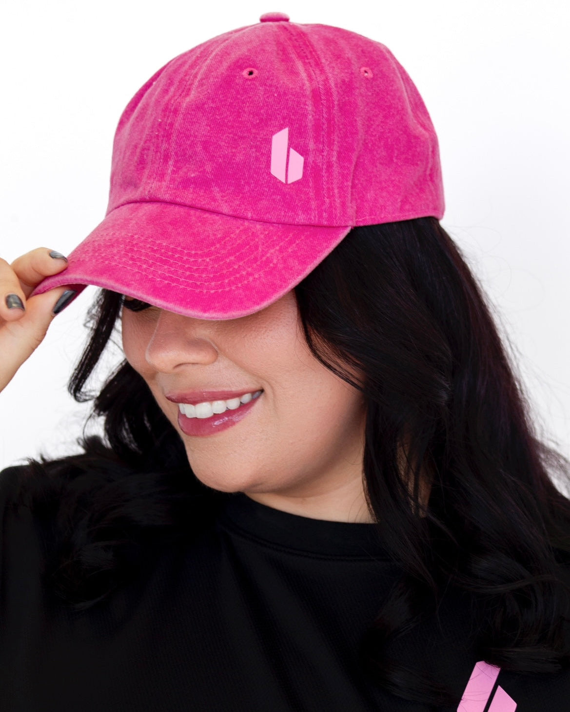 Person wearing a pink cap with a logo on a white background