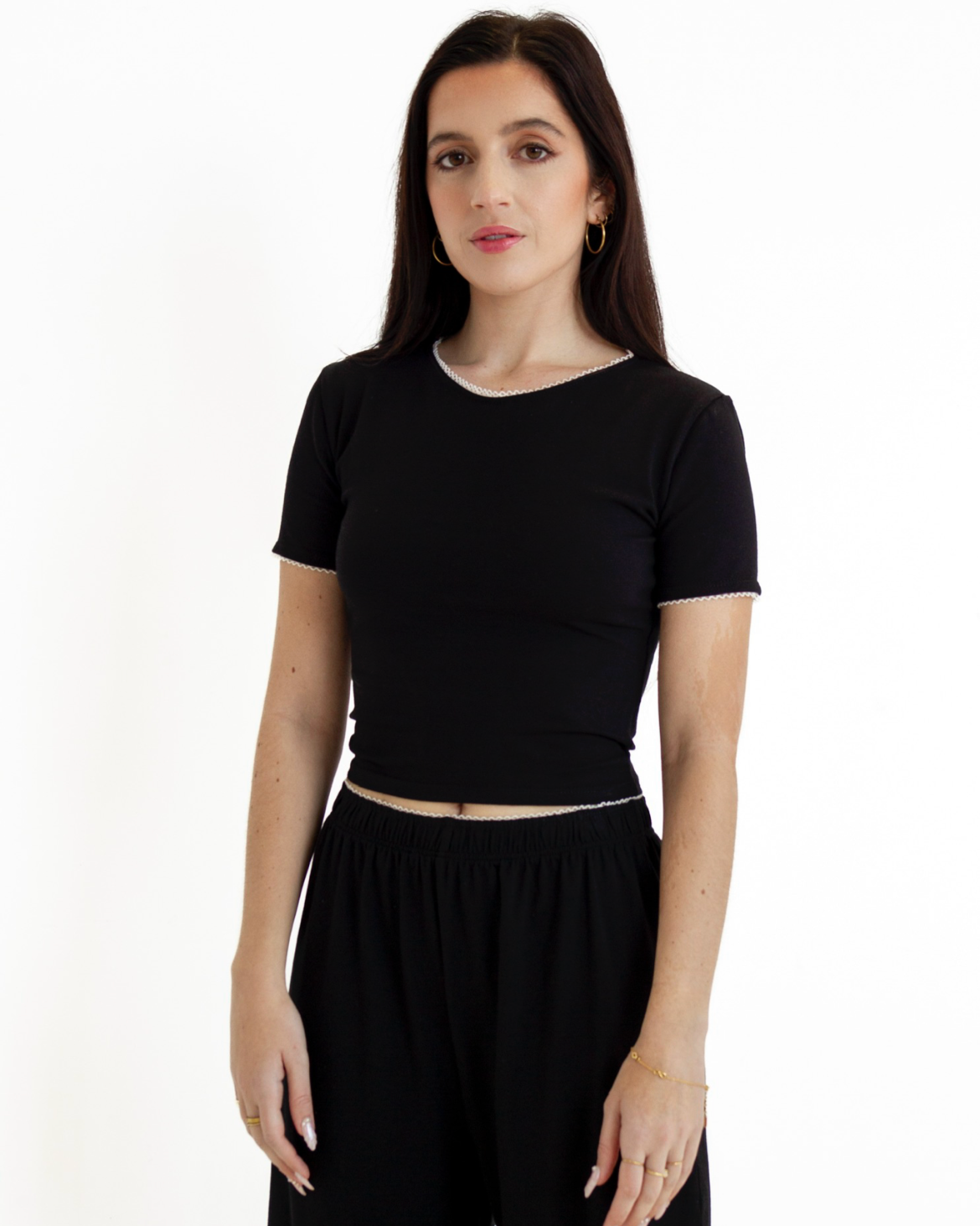Woman wearing a black top and black pants on a white background