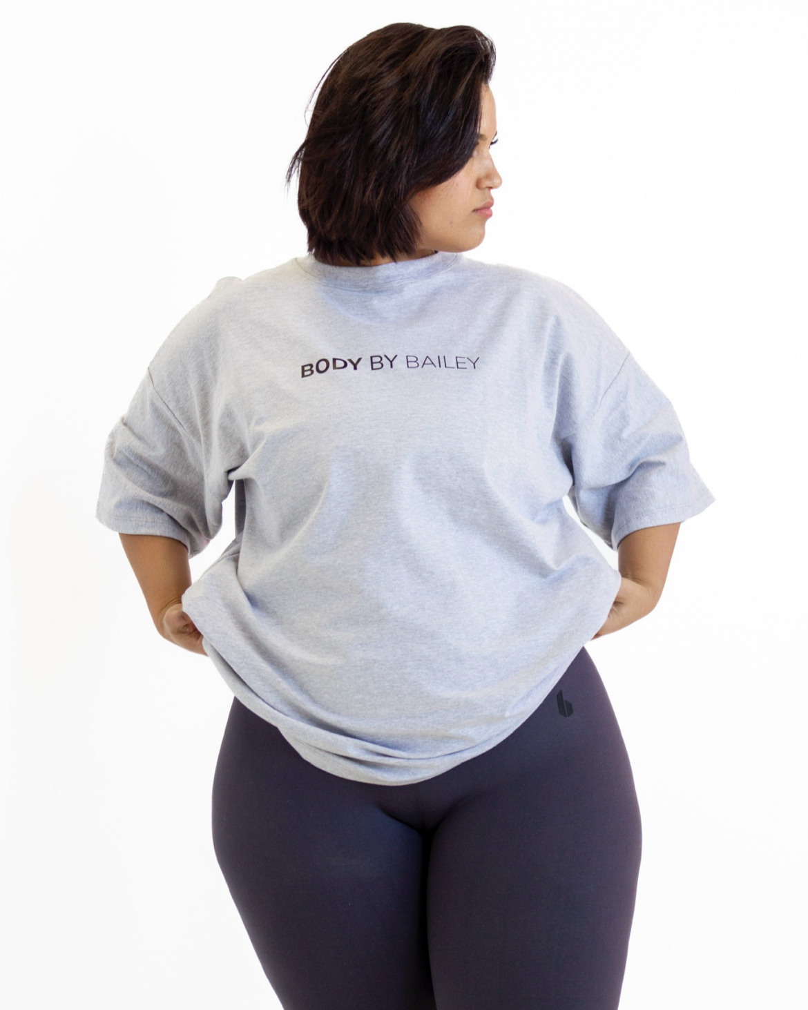 Person wearing a light gray sweatshirt with text on the back, standing against a white background