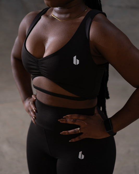 Person wearing a black sports bra and leggings with a brand logo.