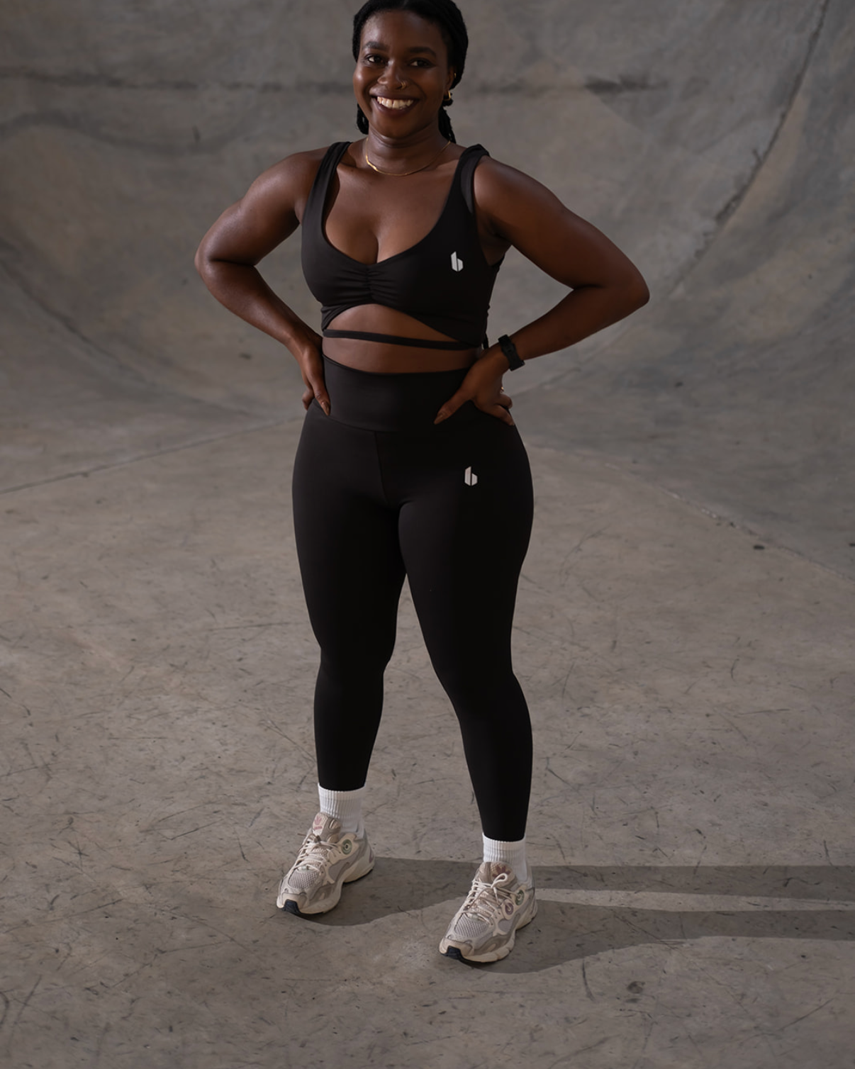 Person wearing a black sports bra and leggings standing on a concrete surface.