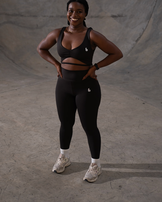 Person wearing a black sports bra and leggings standing on a concrete surface.