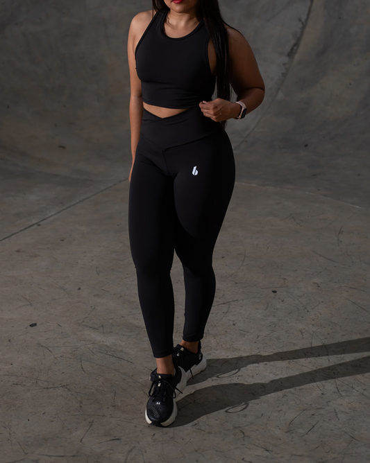 Woman in black athletic wear standing against a gray background