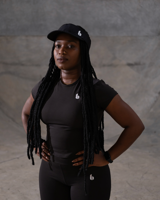 Person wearing a black cap and black outfit with a gray background