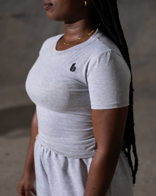 Person wearing a gray t-shirt with a logo on a neutral background