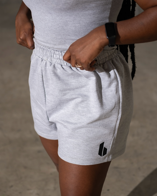 Person wearing gray shorts with a small logo on a neutral background