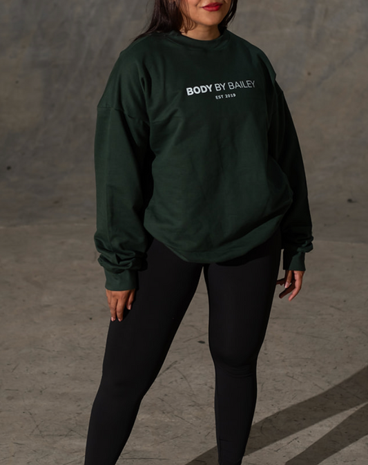 Person wearing a dark green sweatshirt with text on it against a plain background
